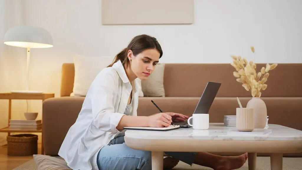 Woman writing on a small table with laptop