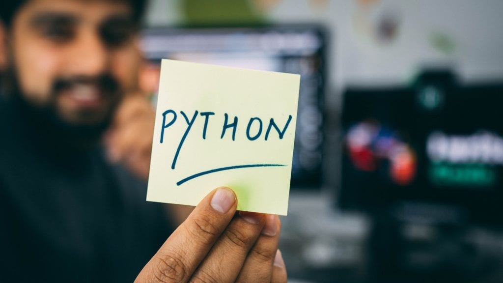 man holding a sticky note with Python written on it